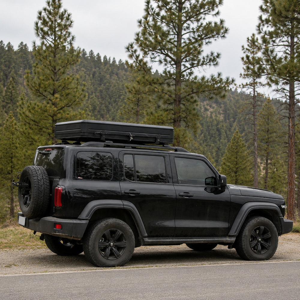 Closed TrailNest aluminum rooftop tent mounted on an SUV beside a forest road