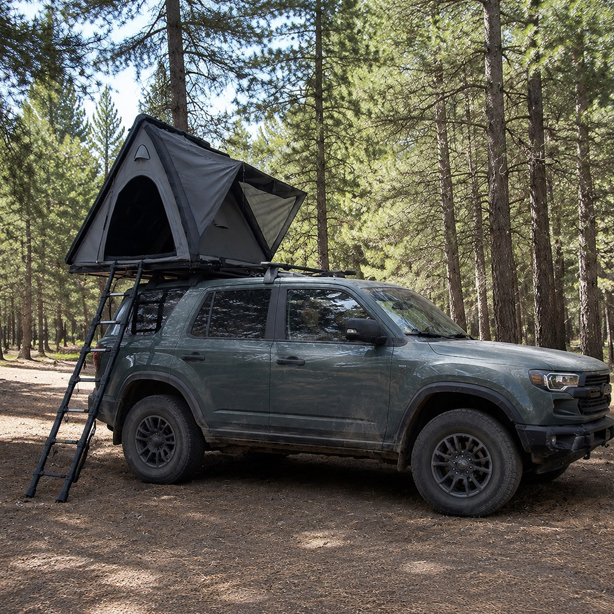 TrailNest Wedge 132 hard-shell rooftop tent open on an SUV in a pine forest.